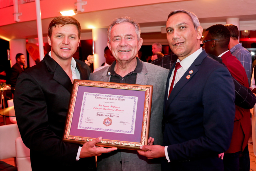 Dylan Tommy, President of Lifesaving South Africa, presenting official patronage to Gareth Wittstock on behalf of HSH Princess Charlene, with Gavin Varejes, President of the Princess Charlene of Monaco Foundation South Africa.